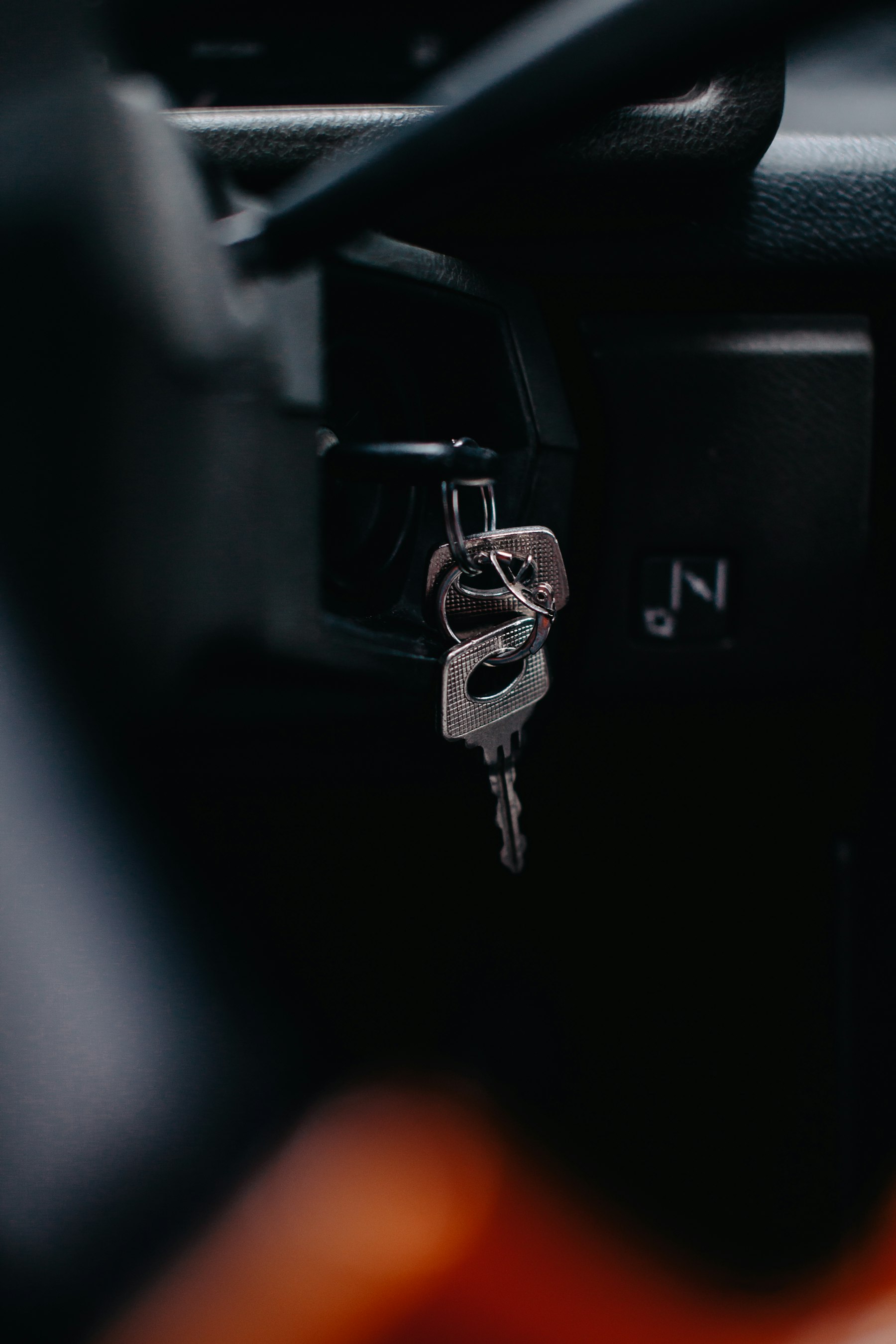 A silver key resting on a black car
